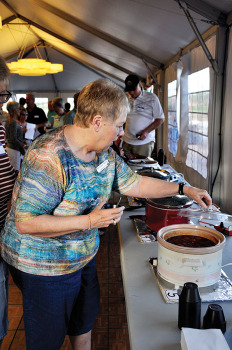 Barb Drury scooping a sample of chili for tasting. undefined