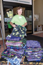 Health Fair volunteer distributes free tote bags to fairgoers.