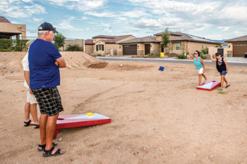Guy Shelton and Rich Osterland are being shown by their wives Debbie Shelton and Jeanne Osterlund how to play corn bag toss.