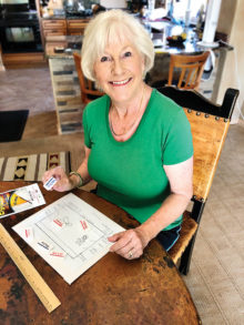 Wondering what Susan is doing in the photo? Susan prefers to design the actors’ blocking (movement on stage) before rehearsals begin. Starting with a diagram of the stage with the set pieces, she moves the “dominoes” with the characters' names around the diagram, and then makes notes for each actor. (Photo by Terry Sterling)