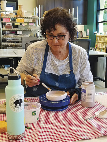 A student applies glaze to her project.